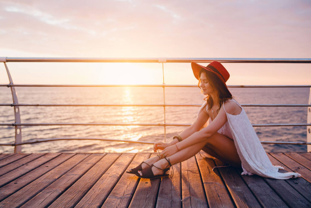 Voyageuse célibataire souriante sur le pont d'un bateau de croisière au coucher du soleil