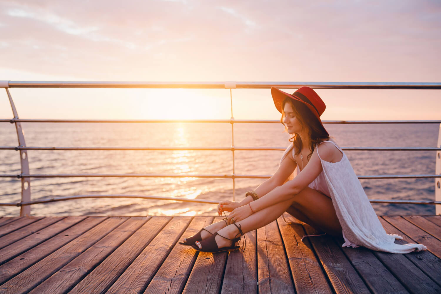 Voyageuse célibataire souriante sur le pont d'un bateau de croisière au coucher du soleil