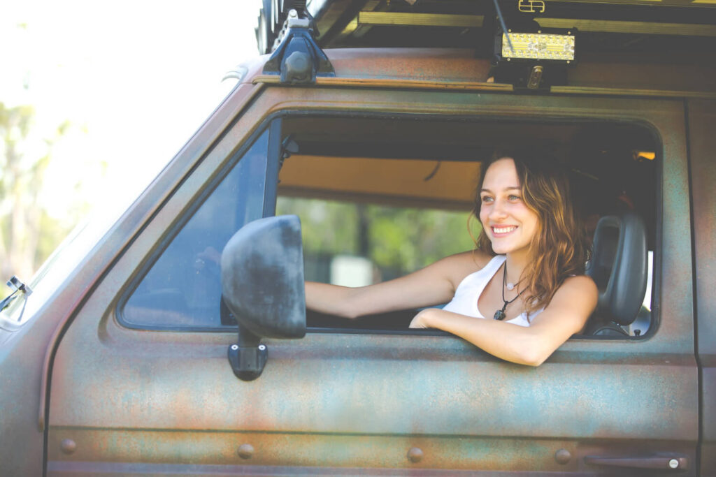 Camping-car femme seule : guide complet pour voyager en toute sécurité 1 Femme conduisant un camping-car seule sur une route panoramique, symbole de liberté et d'autonomie féminine