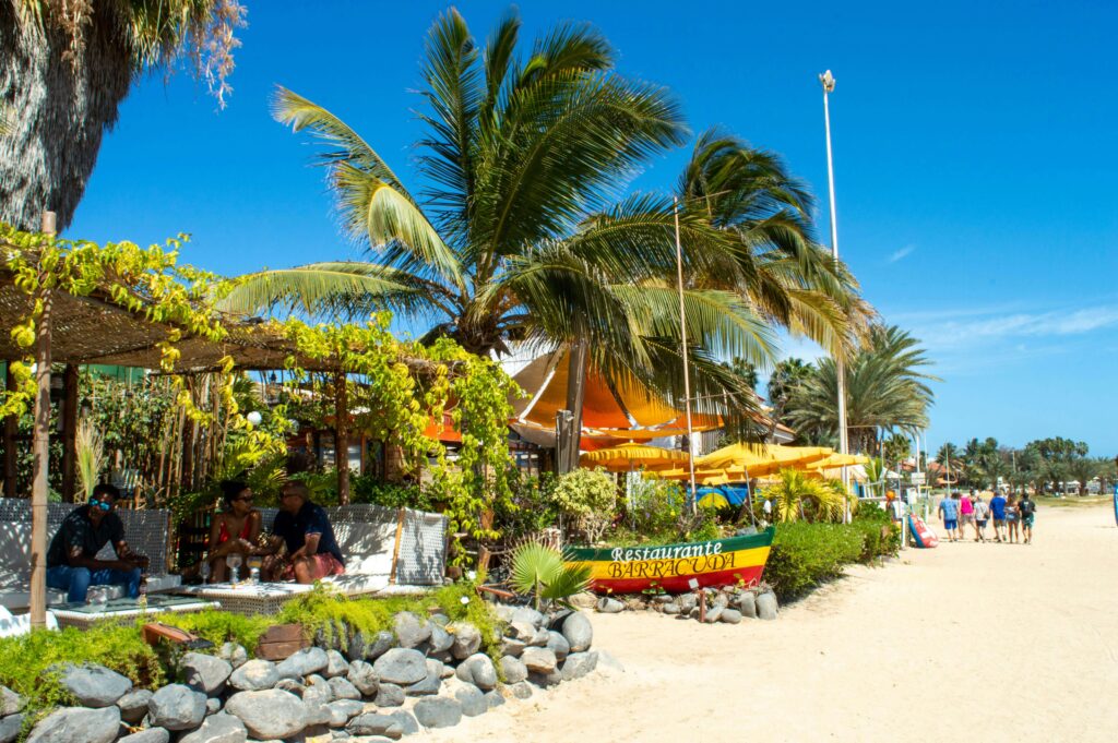 Plage colorée et paisible au Cap-Vert avec des habitants, illustrant la sécurité et l'ambiance tranquille de l'archipel pour les touristes.