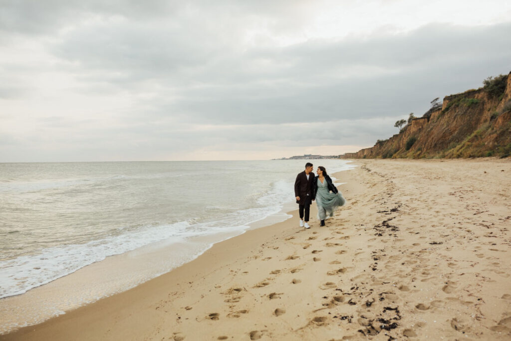 Une plage célèbre et quasi déserte en automne, avec un seul couple se promenant, illustrant le calme du voyage hors saison.