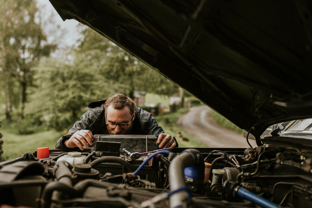Odeur d'œuf pourri dans le camping-car : d'où vient-elle ? 4 Camping-cariste inspectant le compartiment de la batterie cellule de son véhicule avec une expression inquiète.