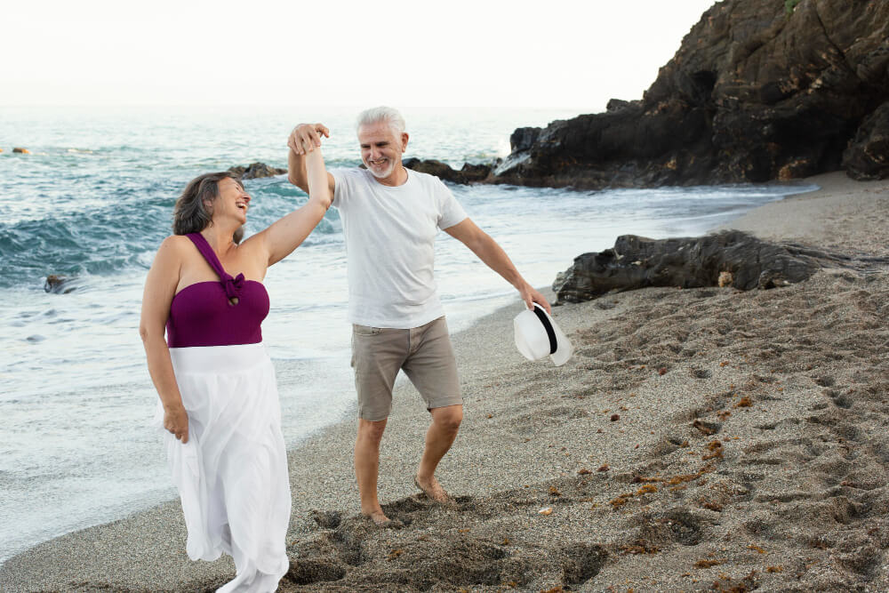 Quels sont les 10 pays qui attirent le plus les retraités ? 1 Couple de retraités souriants sur une plage ensoleillée, symbolisant une retraite à l'étranger.