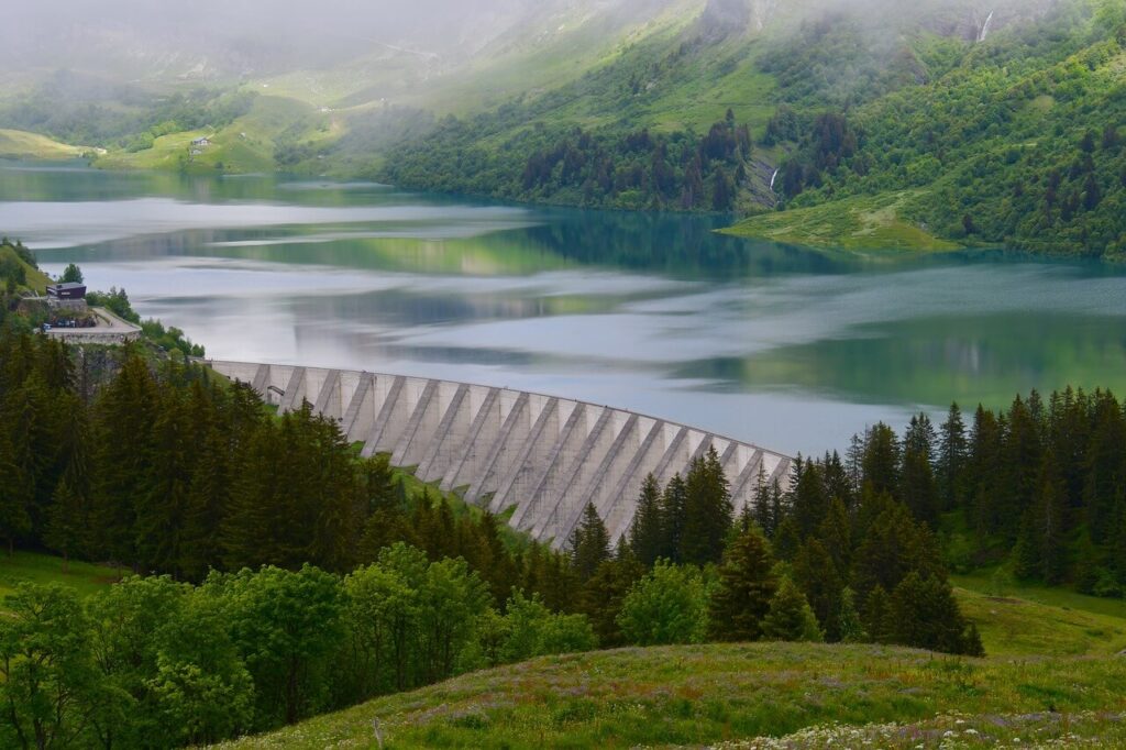 Vue panoramique du Barrage de Roselend et de son lac turquoise, avec la route qui serpente au premier plan.