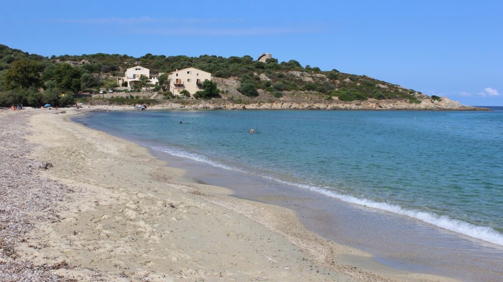 Plage de Lozari en Corse, eau turquoise, avec des vagues qui se forment près du bord.
