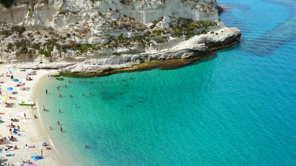 Plage paradisiaque de Tropea en Calabre, avec des touristes se baignant.
