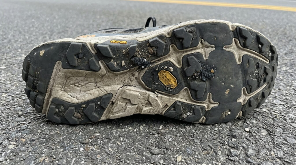 Semelle de chaussure de trail montrant des crampons limés et arrachés après une utilisation intensive sur route goudronnée