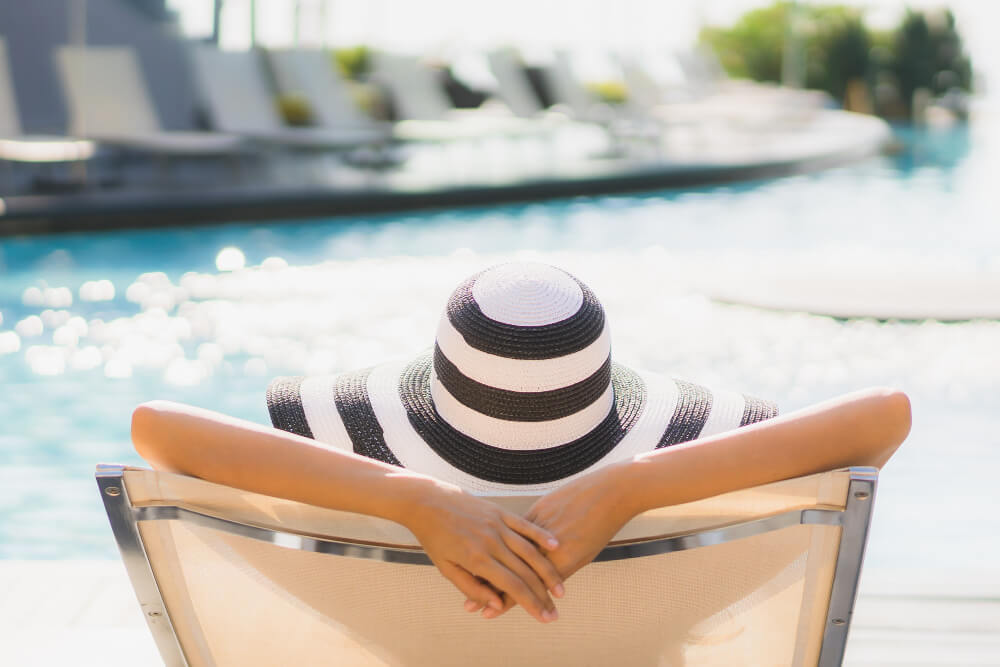 Voyageurs détendus au bord d'une piscine dans un complexe hôtelier tout compris, symbole de vacances sans stress.