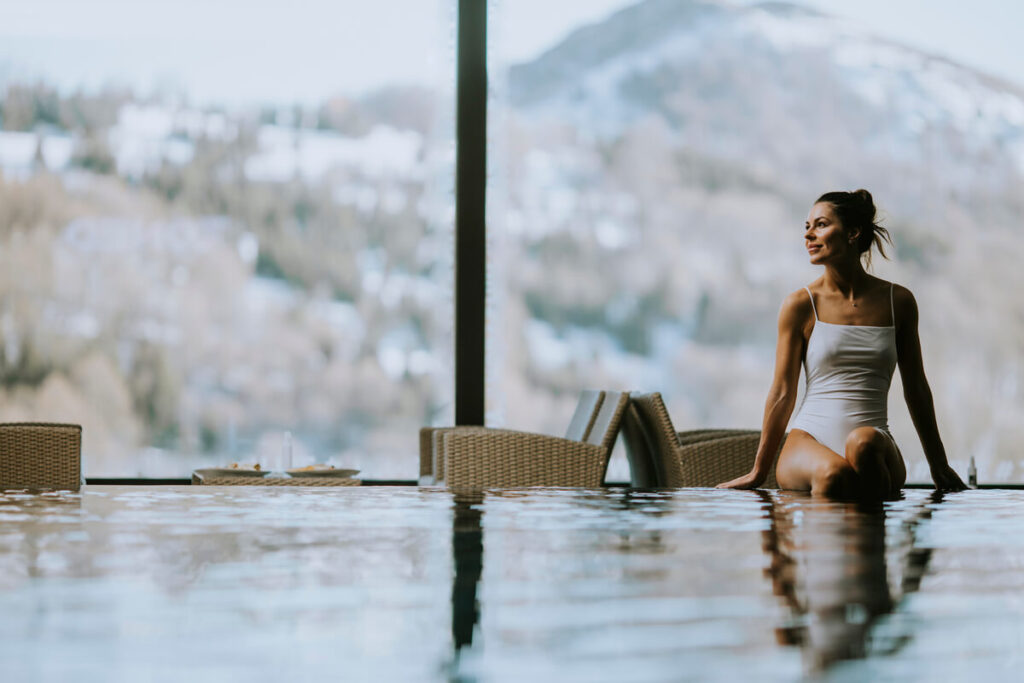 Une piscine extérieure chauffée dans un hôtel de luxe des Alpes face aux montagnes enneigées.