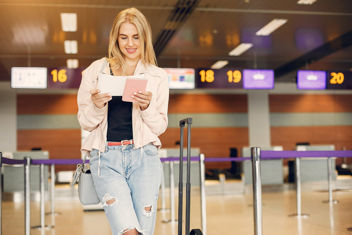 Un voyageur consultant l'application Ryanair sur son smartphone à l'aéroport devant la porte d'embarquement.