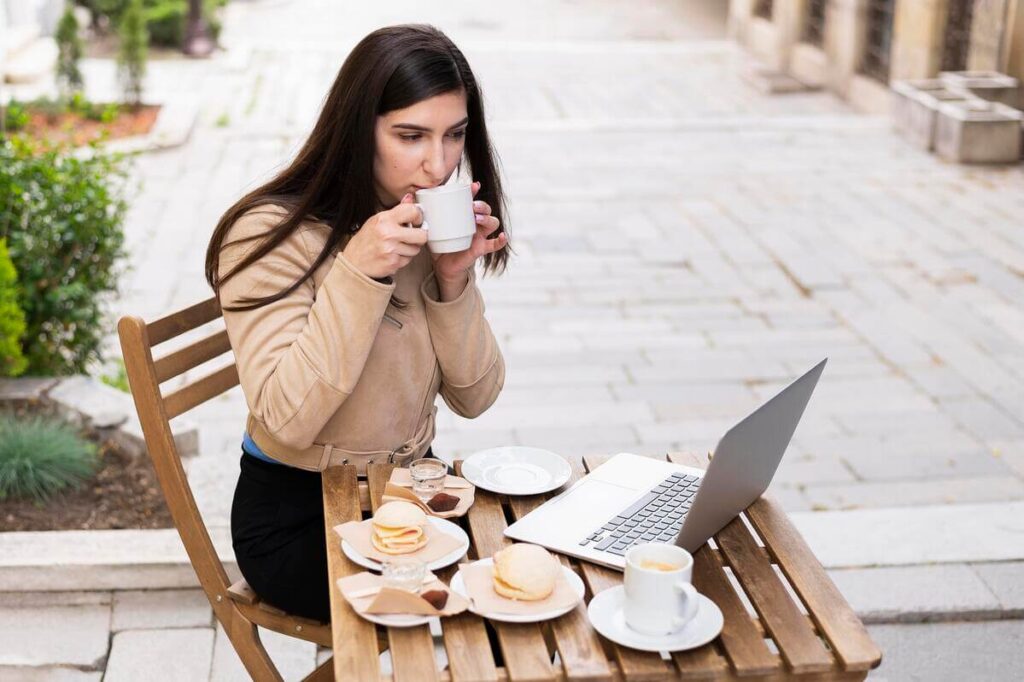 Une personne profitant d'une pause café tout en gérant ses projets professionnels en voyage.
