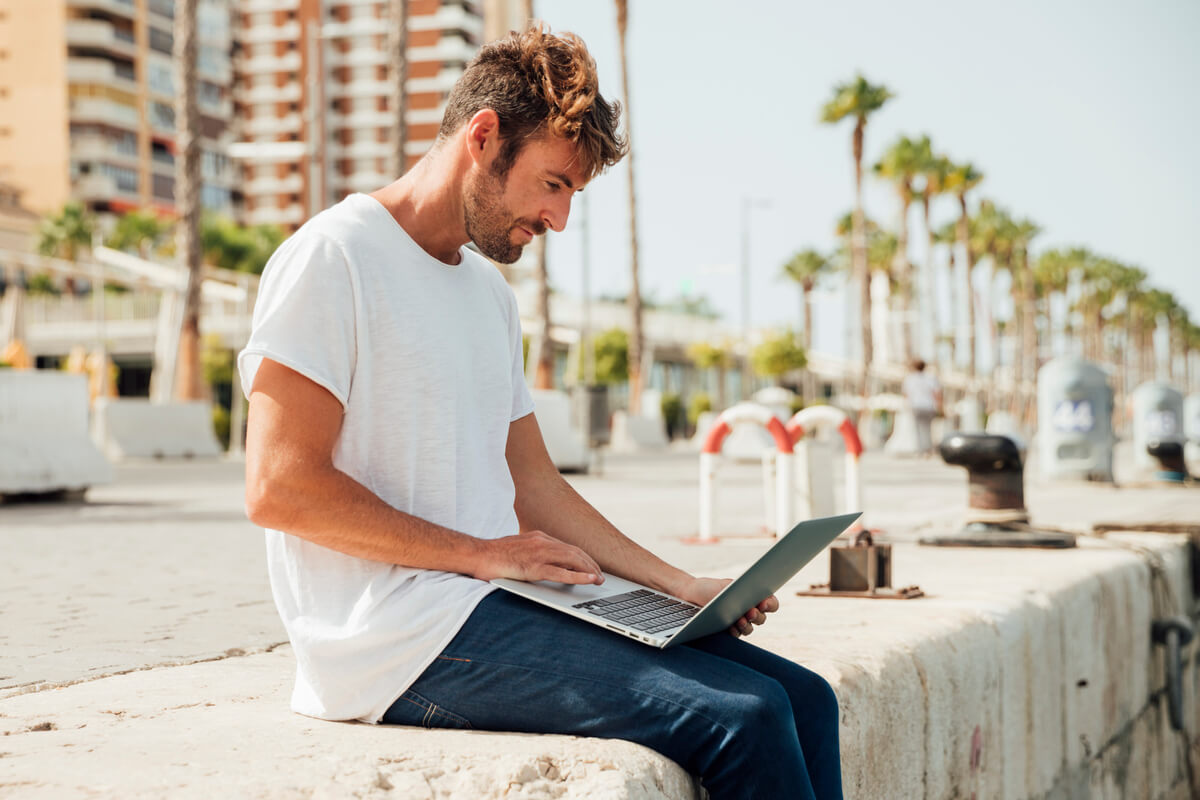 Un nomade numérique travaillant sur son ordinateur portable dans un espace de coworking face à la mer.