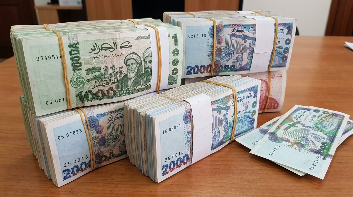 Liasse de billets de banque en dinars algériens sur une table.