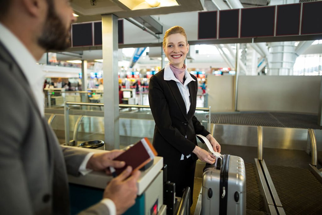 Enregistrement en ligne Air France non disponible : causes, solutions et aéroport 4 Passagers utilisant une borne tactile en libre-service dans le terminal d'un aéroport pour imprimer leur carte d'embarquement.