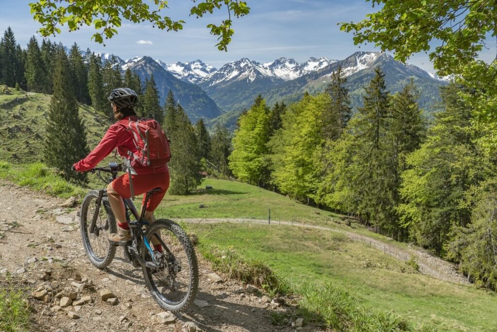 Que faire dans le Jura pour un séjour nature réussi 3 Un vététiste parcourt un sentier en crête offrant une vue panoramique sur les montagnes du Jura.
