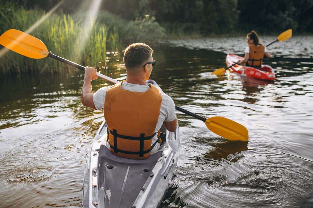 Promeneurs en kayak sur une rivière bordée d'arbres lors d'un séjour nature près de Prayssas.